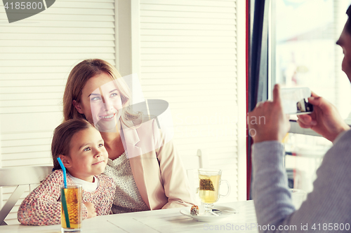 Image of happy family picturing by smartphone at restaurant