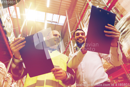 Image of worker and businessmen with clipboard at warehouse