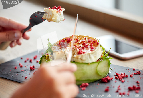 Image of woman eating goat cheese salad at restaurant