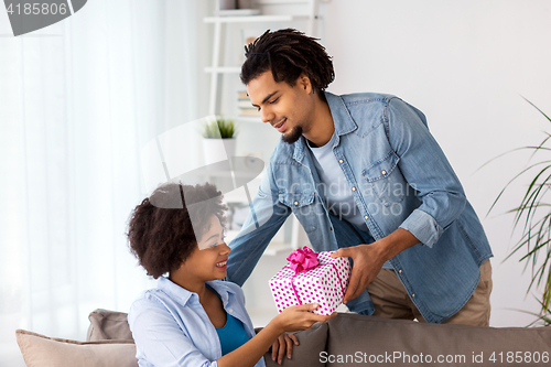 Image of happy couple with gift box at home