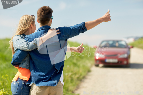 Image of couple hitchhiking and stopping car on countryside