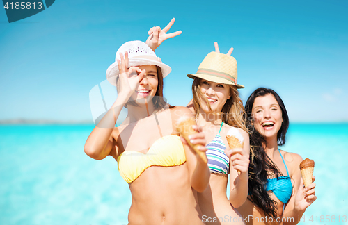 Image of group of smiling women eating ice cream on beach