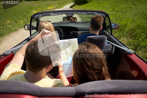 Image of happy friends with map driving in convertible car