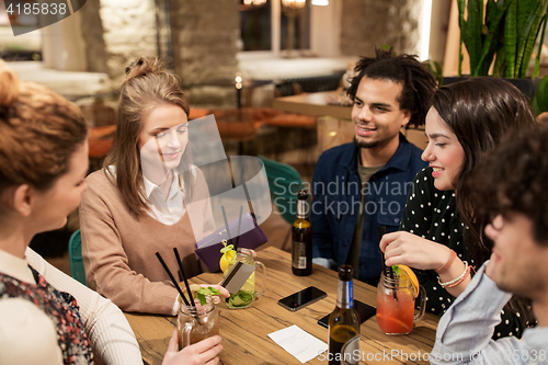 Image of friends with drinks, credit card and bill at bar