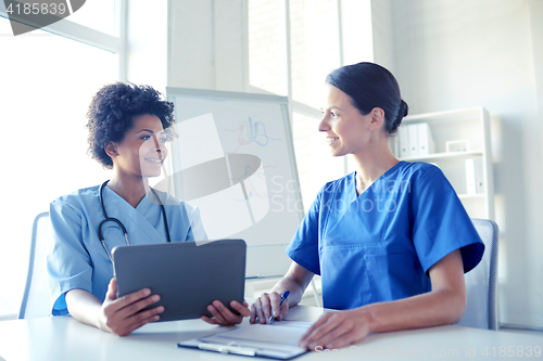 Image of happy doctors with tablet pc meeting at hospital