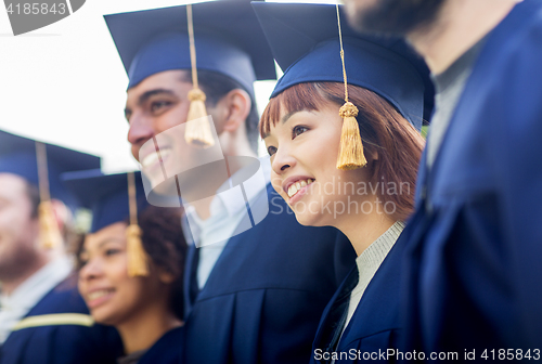 Image of happy students or bachelors in mortar boards