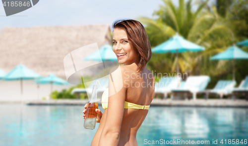 Image of happy woman with bottle of drink on summer beach