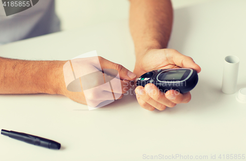 Image of close up of man checking blood sugar by glucometer