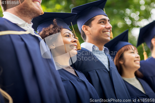 Image of happy students or bachelors in mortar boards