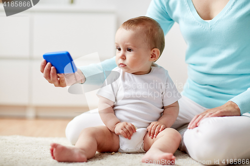 Image of mother showing smartphone to baby at home