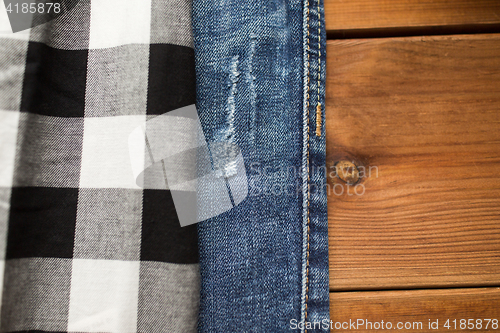 Image of close up of checkered shirt and jeans on wood