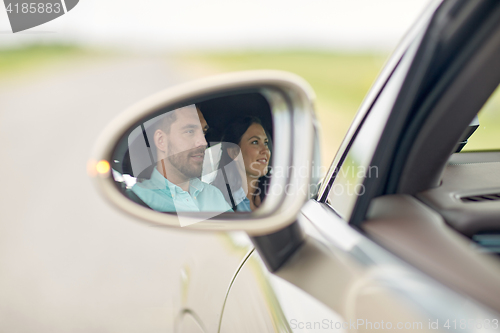 Image of side mirror reflection of happy couple driving car