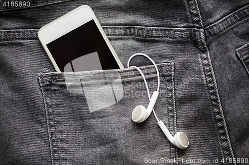 Image of smartphone and earphones in denim or jeans pocket