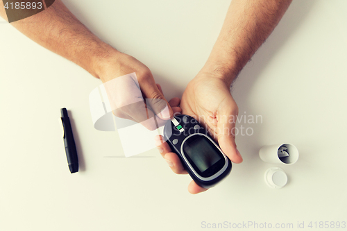 Image of close up of man checking blood sugar by glucometer