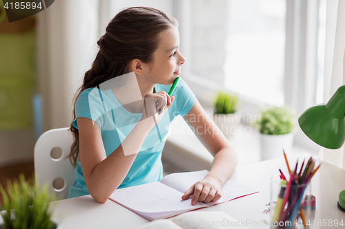 Image of happy girl with book writing to notebook at home