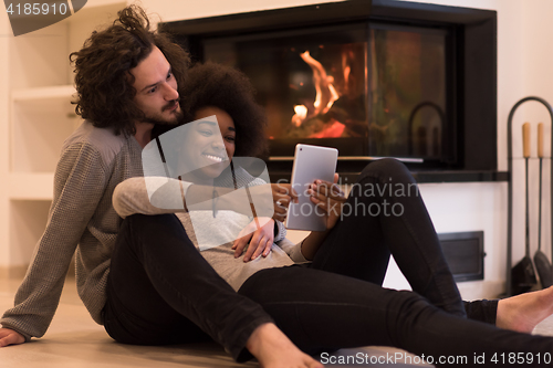 Image of multiethnic couple used tablet computer on the floor