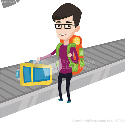 Image of Man picking up suitcase on luggage conveyor belt.