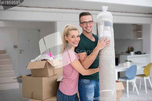 Image of couple carrying a carpet moving in to new home