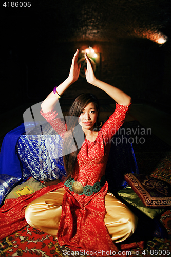 Image of young pretty asian girl in bright colored interior on carpet view, oriental concept