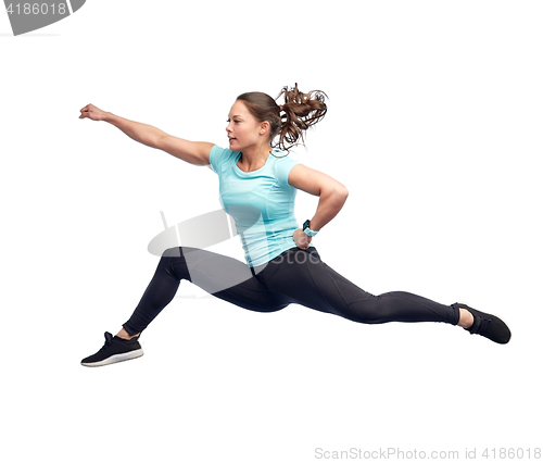 Image of happy sporty young woman jumping in fighting pose