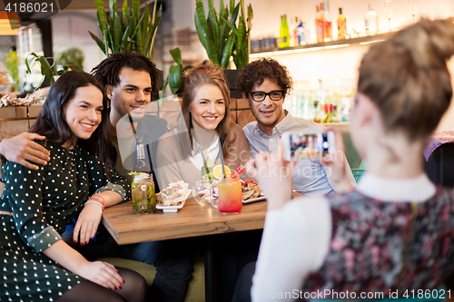 Image of friends with smartphone photographing at cafe