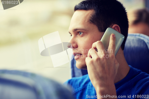 Image of happy man in travel bus and calling on smartphone