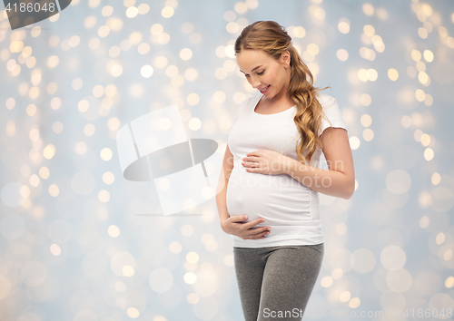 Image of happy pregnant woman touching her big belly