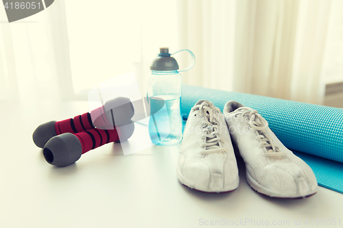 Image of close up of bottle, dumbbells, sneakers and mat