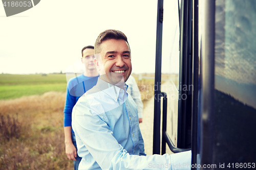 Image of group of happy male passengers boarding travel bus