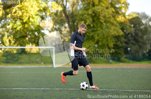 Image of soccer player playing with ball on football field