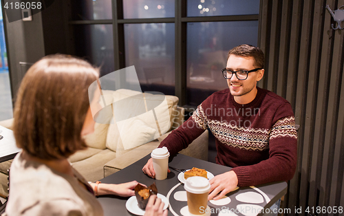 Image of happy couple with coffee eating cake at cafe