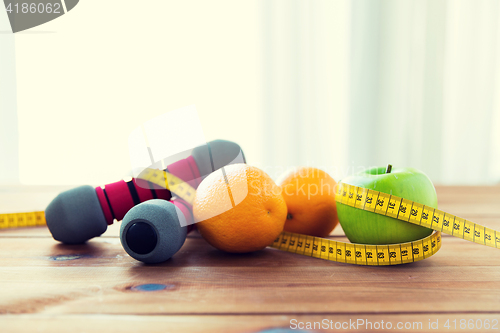 Image of close up of dumbbell, fruits and measuring tape