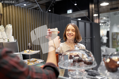 Image of happy woman taking coffee cup from seller at cafe