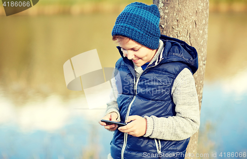 Image of happy boy playing game on smartphone outdoors