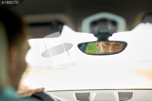 Image of rearview mirror reflection of man driving car