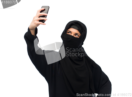 Image of muslim woman in hijab taking selfie by smartphone