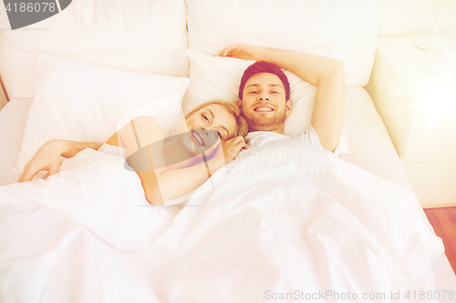 Image of happy couple lying in bed at home