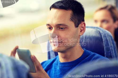 Image of happy man sitting in travel bus with smartphone