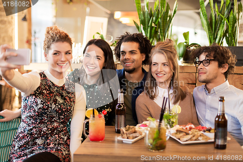 Image of friends taking selfie by smartphone at bar or cafe