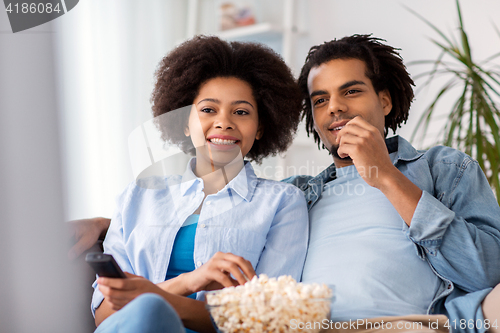 Image of smiling couple with popcorn watching tv at home