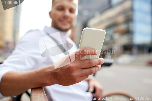 Image of close up of man texting on smartphone in city