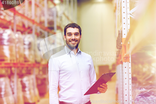 Image of happy businessman with clipboard at warehouse