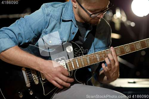 Image of close up of man playing guitar at studio rehearsal