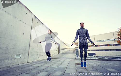 Image of man and woman exercising with jump-rope outdoors