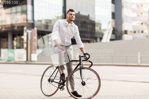 Image of man with bicycle and headphones on city street