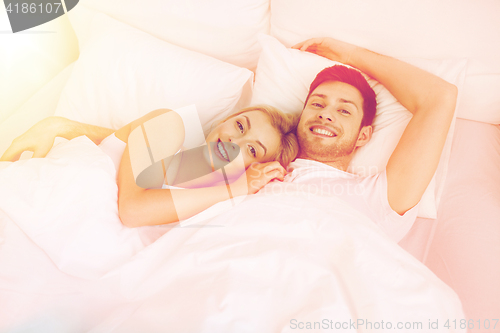 Image of happy couple lying in bed at home