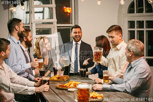 Image of Group of friends enjoying evening drinks with beer