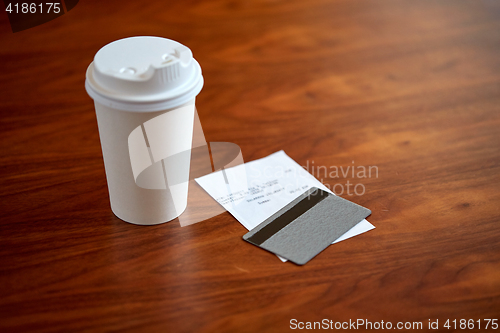 Image of coffee in paper cup, bill and credit card on table