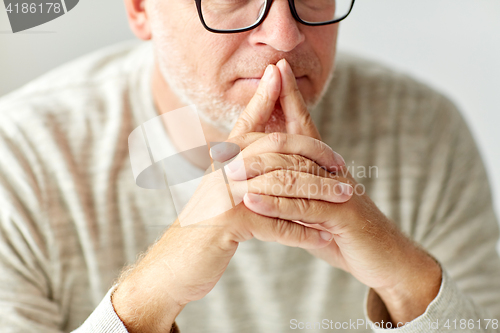 Image of close up of senior man in glasses thinking