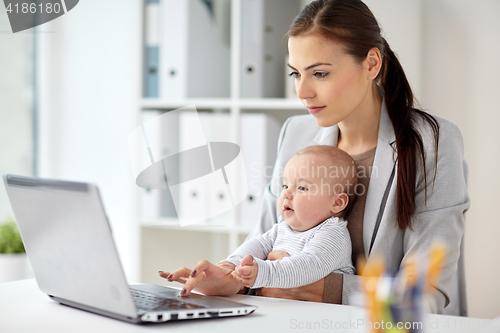 Image of happy businesswoman with baby and laptop at office